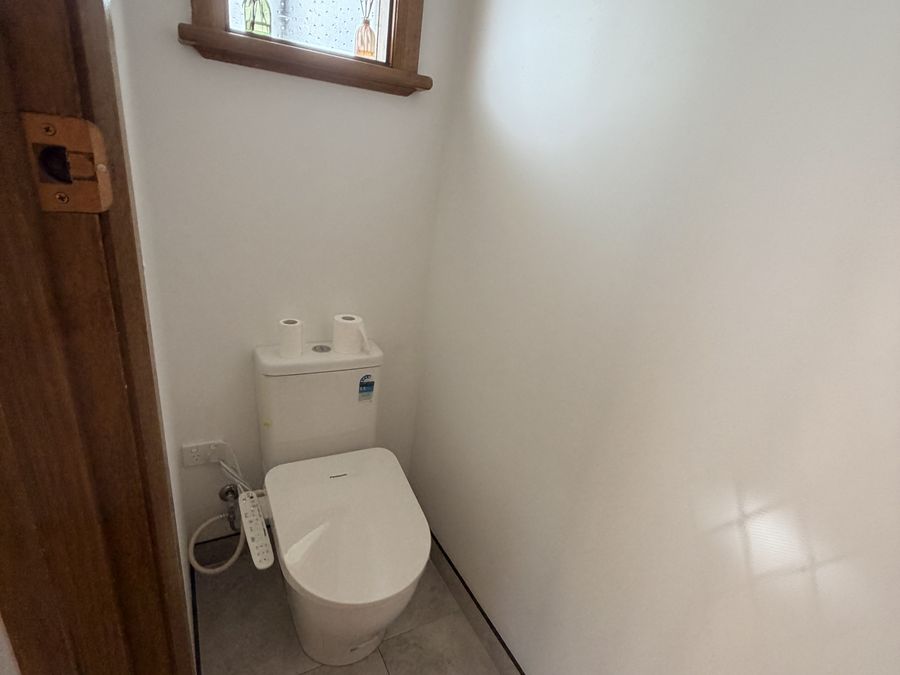 Separate toilet with new floor tiling and the original timber door retained